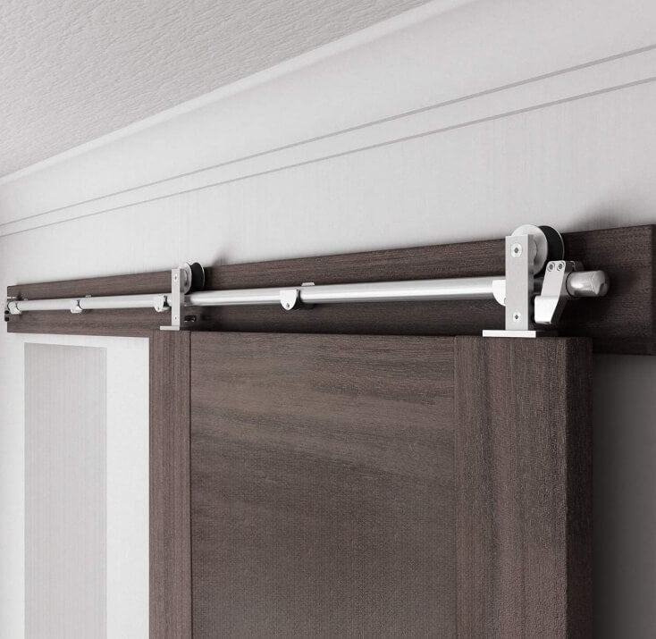 The barn door hardware kit is installed on the door and rolls