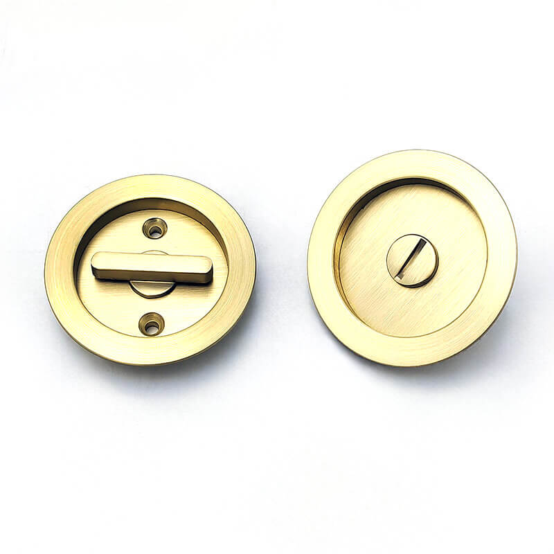 The lock plates of two golden circular pocket door locks