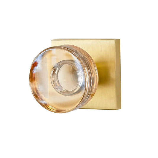 Gold door handle with clear glass knob on a white background