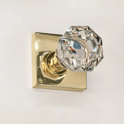 Crystal door handle on a gold finish plate against a white background